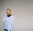 blonde woman in blue shirt with headphones looks at the camera. music fan. studio shot. square composition. Music lover theme banner with copy empty space