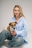 Fototapeta Konie - Blonde Woman and dog Jack Russell terrier studio portrait. Cute friends. Gray background