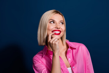 Sticker - Photo of dreamy minded cute girl dressed pink shirt finger on red lips look at logo empty space isolated on dark blue color background