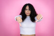 © Irene - African american woman wearing casual sweater over pink background with angry face, negative sign showing dislike with thumbs down