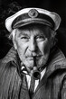 Schwarz-Weiß Portrait eines alten traditionellen Seemannes mit Bart, Seemannskappe Hut und Pfeife