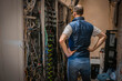 © Климов Максим - A technician looks at a rack of server equipment, viewed from the back. A man with his hands on his belt is thinking about how to solve a problem in a data center.
