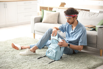 Canvas Print - Male student taking book from backpack at home