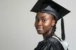 Happy african american female graduate student in graduation gown and cap on grey background
