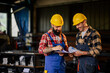 © Zamrznuti tonovi - Smiling men in workshop reading new production plan for metal factory.
