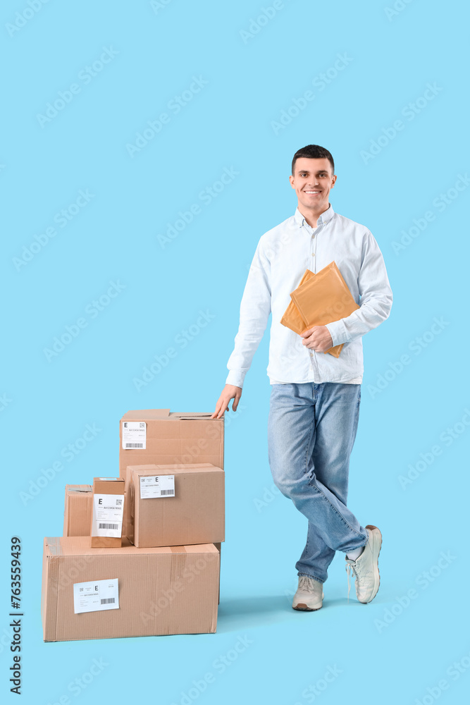 Male online store seller with envelopes and parcel boxes on blue background