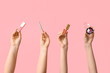 © Pixel-Shot - Female hands with eyeshadows palette, lip glosses and eyeliner on pink background