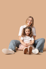 Poster - Mother and daughter sitting on floor on beige background. Mother's Day