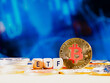 Bitcoin ETF. coin stands against a blurred blue background with financial graphs. Other coins are scattered around it. The image conveys a modern approach to finance and investment on stock marketa