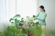 © One - 観葉植物の世話をする20代女性