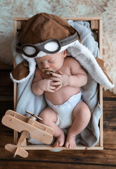 Sticker - Cute newborn baby wearing aviator hat with toy sleeping in wooden crate, top view