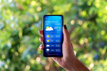 woman outdoors checking the weather forecast on an app on her mobile phone.
