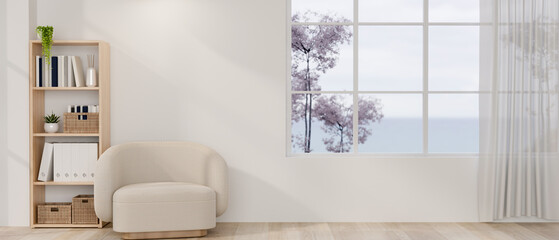 The interior design of a minimalist Japandi living room features a cozy armchair and a white wall.