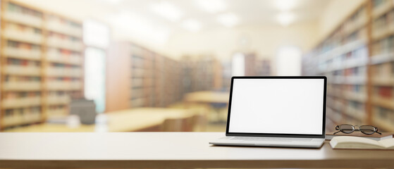 a wooden table features a laptop computer mockup over a blurred background of a school library.