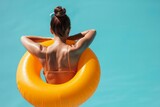 Fototapeta Tęcza - A woman in a bikini posing with an inflatable pool ring float. Summer holiday lifestyle