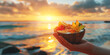 Tropical Fruit Salad in Coconut Bowl Held Against a Beach Sunset