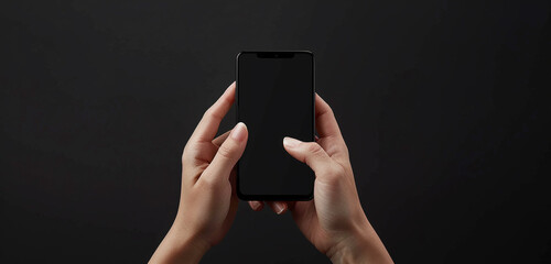 Wall Mural - Front view of a person's hands gripping a black screen mobile device, fingers elegantly positioned, against a pure black backdrop, emphasizing the sleek and stylish design