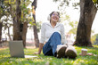 © bongkarn - A carefree, happy young Asian woman is enjoying the music on her headphones in a green park.