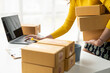 © ArLawKa - female online store small business owner The seller packs the parcel behind the shipping box. Preparing packages for SME e-commerce delivery service concept. Close-up.