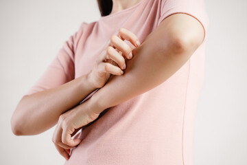 A woman with a pink shirt is scratching her arm