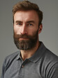 Portrait of a casually dressed bearded man with a confident look and a grey polo shirt