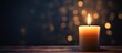 A flickering candle on a wooden surface with defocused lights