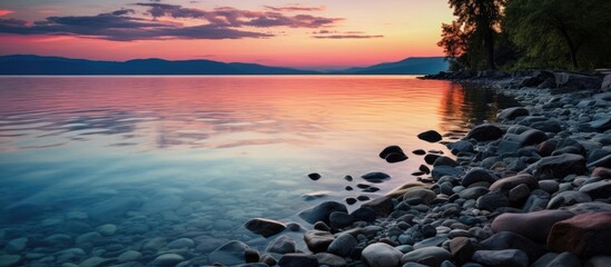 Poster - A tranquil lake with rocks and trees under the sunset