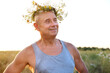 happy cool satisfied trendy funky hipster mature man of 60 years old smiles in T-shirt, cute wreath wildflowers, daisies, natural crown on head, image faun, satyr in sunlight, connection with nature
