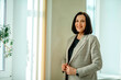 © Айман Дайрабаева - Smiling business. smiling businesswoman. entrepreneur stands in a jacket in the office lobby by the window