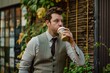 man in a vest and tie sipping coffee from an eco cup