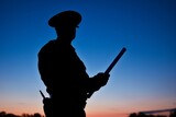 Fototapeta Sawanna - photo of an officers silhouette holding a baton at dusk