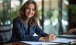 © khwanchai - Happy satisfied middle aged professional business woman executive ceo manager, lawyer wearing suit sitting at desk signing law document writing signature making legal agreement corporate deal