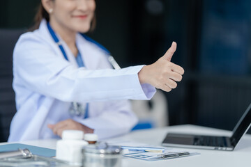 Wall Mural - Portrait of mix race asian middle age female doctor in white lab coat and stethoscope while consult online in laptop. advice on good mental health management and medical treatment costs.