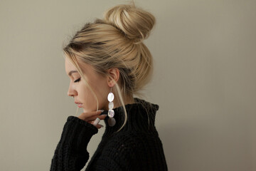 Beautiful young girl wearing warm black sweater and fashion jewellery over pastel background