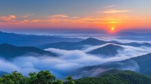Misty Mountain Landscape With Clouds, Fog, And Orange Sunrise Sky Creating A Serene Morning View