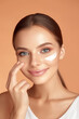 © ImageFlow - A woman with cream on her face, beauty and cosmetology concept with a warm peach background. Generative AI