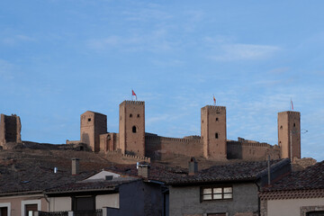 Wall Mural - An ancient castle with tall towers overlooks a modern town, showcasing architectural contrast and historical preservation