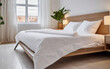 Modern bed with white bed linen in a bright bedroom