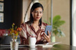 © DragonImages - Businesswoman sitting at cafe table, checking emails on smartphone and writing in planner