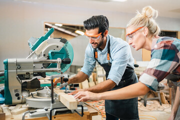 In a carpenter's shop, a skilled man with training in the craft uses tools to perform woodwork, blending occupation, industry, and business.