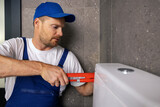 Fototapeta Mapy - plumber handyman working in bathroom installing water closet pipe with wrench