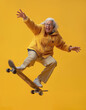 An elderly woman jumping with the skateboard, happy and smiling. youthful energy, subject isolated on light yellow background