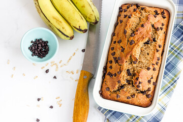 Wall Mural - Banana Oatmeal Healthy Bread with Chocolate Chips in a Baking Tin Top Down Vertical Photo on White Background