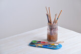Fototapeta Nowy Jork - Jar with brushes and watercolors on wooden table. Great for creative projects or artistic themes