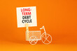 Long-term debt cycle symbol. Concept words Long-term debt cycle on beautiful white paper on clothespin. Bicycle model. Beautiful orange background. Business Long-term debt cycle concept. Copy space.