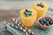 Refreshing and healthy mango smoothie in glasses with coconut flakes and fresh blueberries