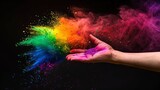 Fototapeta  - Holi festival: A burst of color! A hand throws vibrant rainbow-colored powder, creating a cloud of dust against a black background.