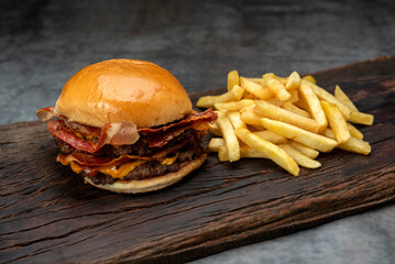 variety of homemade beef burgers with onion cucumber dressings tomato chedar cheese lettuce mayonnaise mustard ketchup barbecue with potato bun and french fries on wooden board