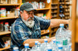 © apratim - A bearded senior man stocking bottled water on the shelves at a supermarket, focused on his retail job.
