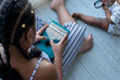 Little girl with African style braids sits and plays the kalimba thumb piano keyboard on floor, view from above